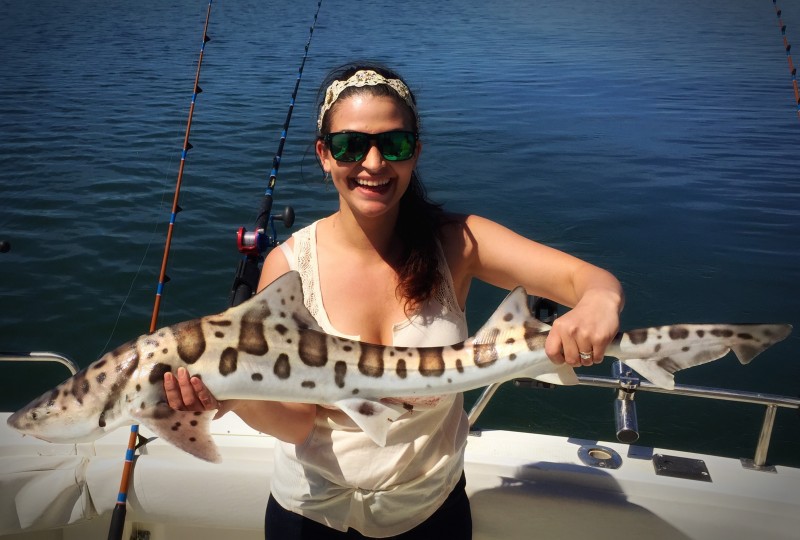 Woman on fishing charter holding leopard shark